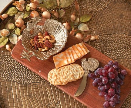 Wooden charcuterie board with cheese, crackers, and grapes on a textured surface