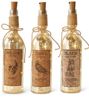 Three decorative bottles with labels and string lights on a white background