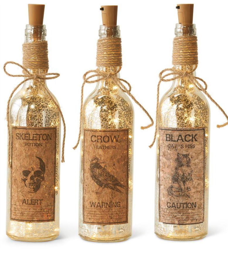 Three decorative bottles with labels and string lights on a white background