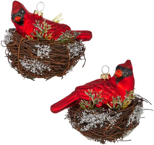 Two red cardinal bird ornaments in a nest on a white background