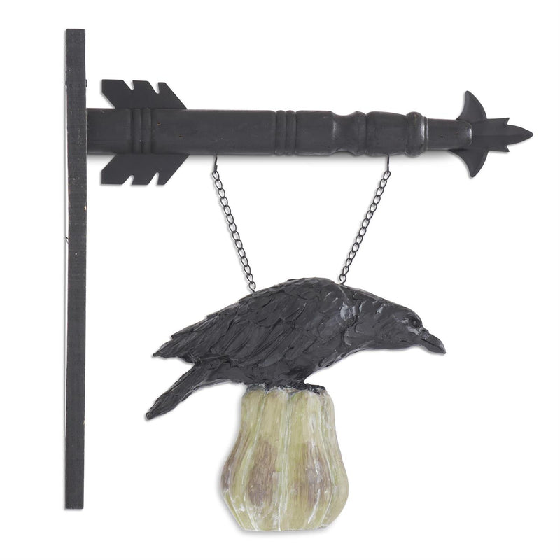 Decorative wall art with a black crow on a rock and an arrow-shaped bracket.
