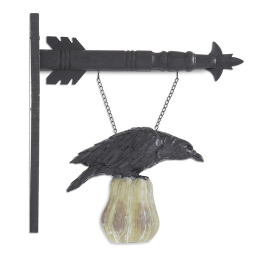 Decorative wall art with a black crow on a rock and an arrow-shaped bracket.
