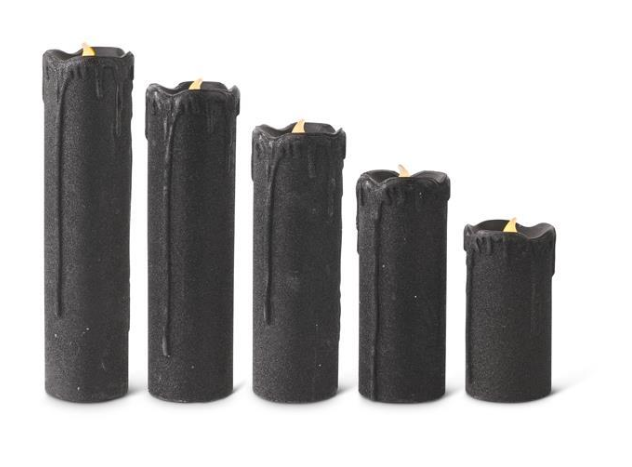 Set of five black candles of varying heights on a white background