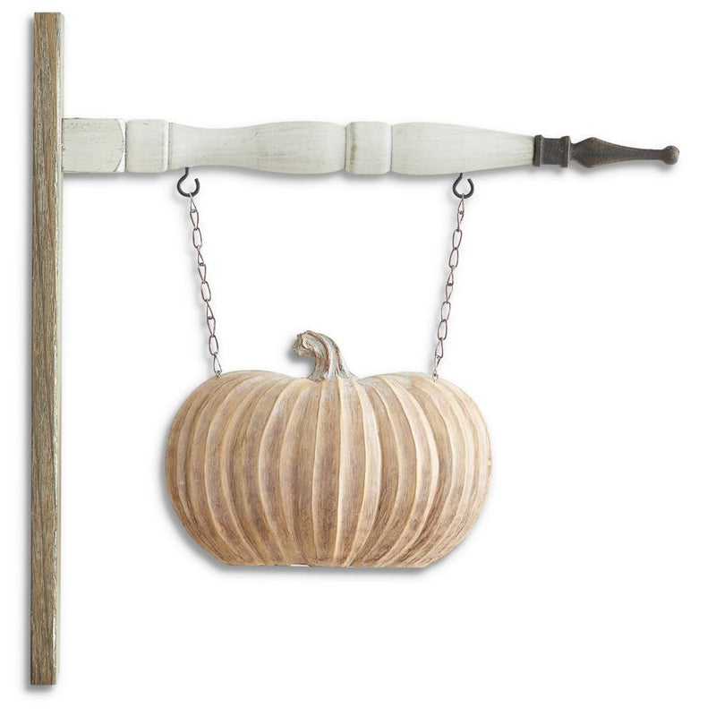 Decorative wooden pumpkin hanging from a strap on a white background
