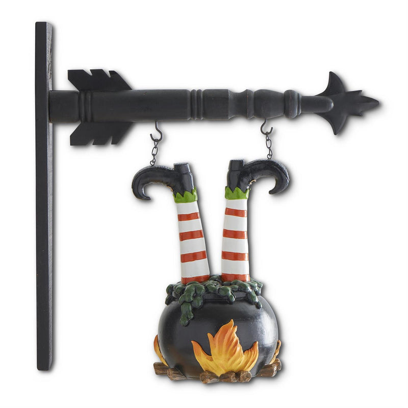 Decorative Halloween ornament with witch legs in a cauldron over a fire on a black key-shaped hook.