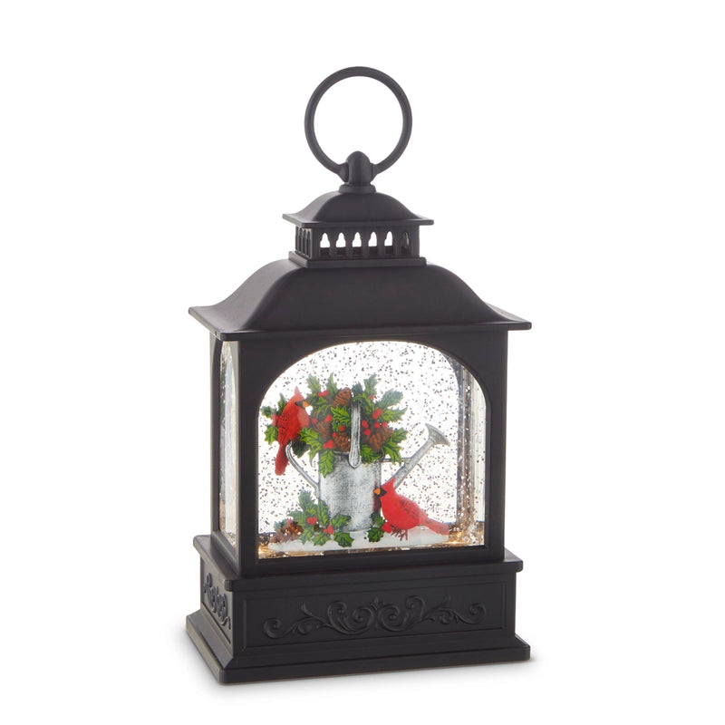 Black lantern with a snow globe featuring cardinals and flowers on a white background