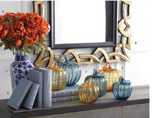 Decorative setup with blue and gold pumpkins, books, and a floral arrangement in a room.