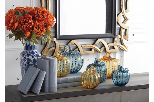 Decorative setup with blue and gold pumpkins, books, and a floral arrangement in a room.