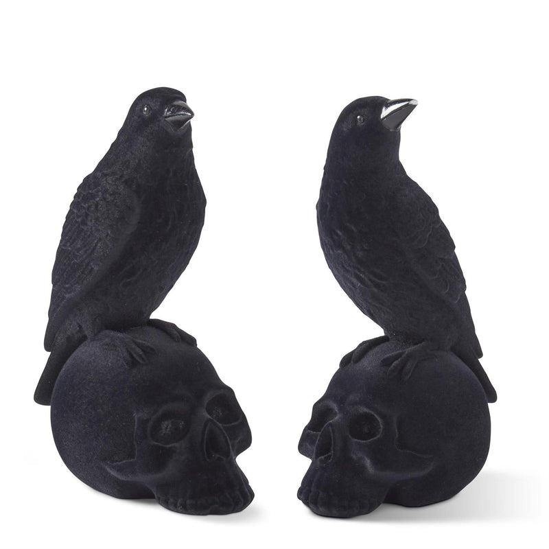 Two black velvet flocked crows perched on top of skull-shaped resin figurines.