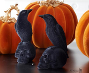 Black decorative crows with skull bases in front of pumpkins
