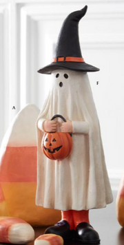 Ghost figurine in a witch hat holding a pumpkin with candy corn in the background