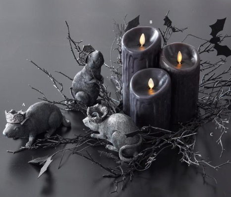 Decorative arrangement with black candles, small animals, and branches on a dark background