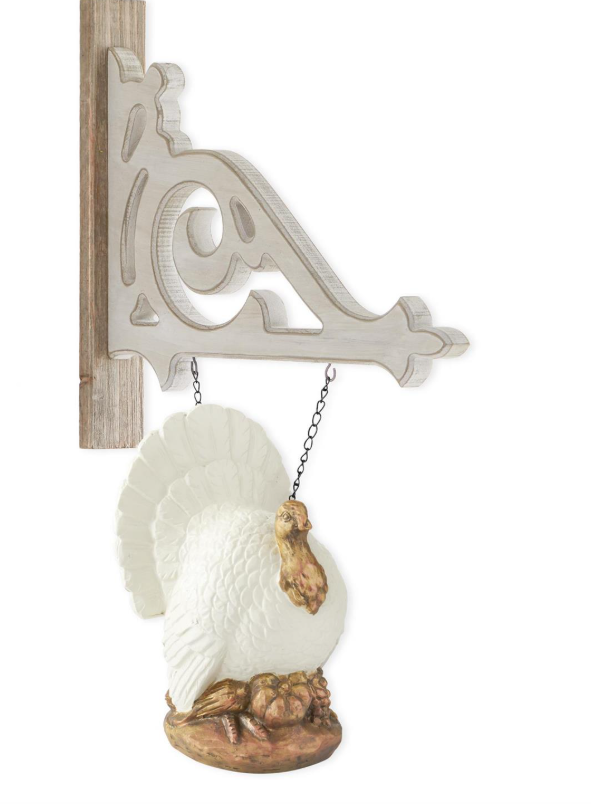 Decorative white turkey hanging from a metal bracket on a white background
