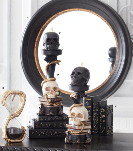 Decorative setup with skulls, books, and an hourglass in front of a mirror.