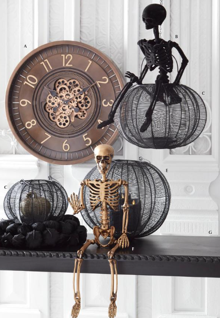 Decorative Halloween scene with skeletons and wire pumpkins on a shelf.