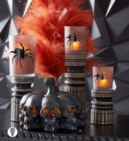 Halloween-themed candles with spider designs and decorative pumpkins on a geometric black background.