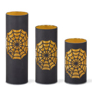 Three black cylindrical candles with gold spider web designs on a white background