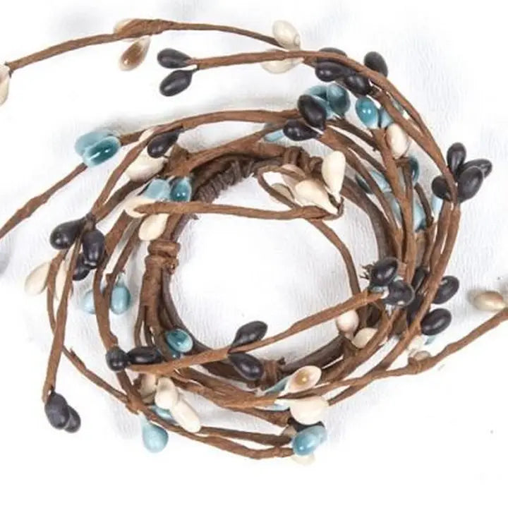 Coiled brown cord with black, blue, and white beads on a white background
