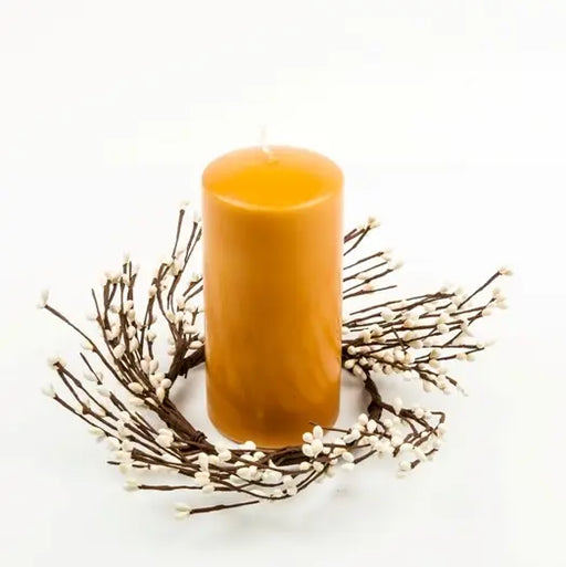 Orange candle on a decorative branch with small white flowers on a white background
