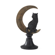 Decorative statue of a black cat sitting on a curved moon with a white background