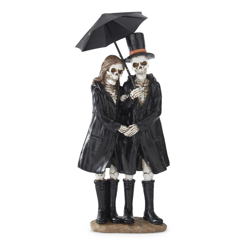 Statue of two skeletons in black coats and boots holding a black umbrella on a white background