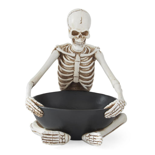 Skeleton holding a black bowl on a white background