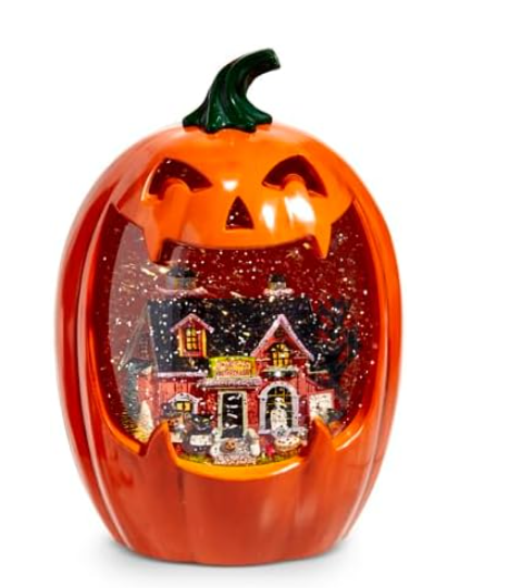 Pumpkin-shaped decorative light with a miniature house inside on a white background