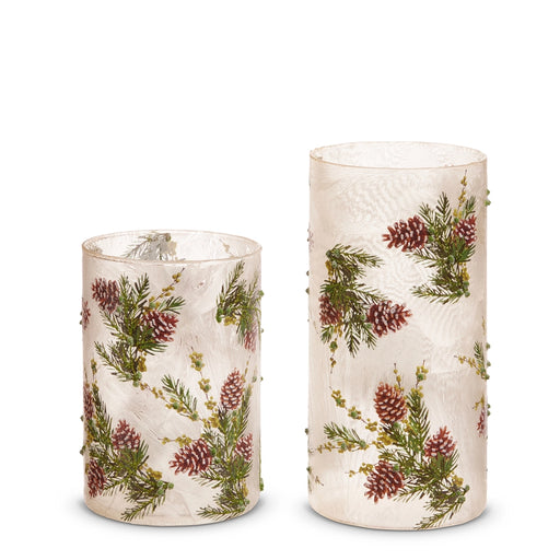 Two cylindrical candles with floral and pine cone pattern on a white background