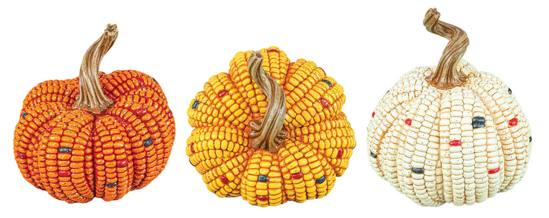 Three decorative pumpkins made from corn kernels, shown side by side on a plain white background. The left pumpkin is orange with small blue and red accents, the middle pumpkin is yellow with small blue and red accents, and the right pumpkin is off-white with small red, blue, and green accents.