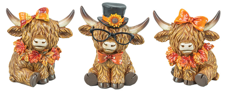 Three decorative Highland cow figurines shown side by side on a plain white background. The left cow wears an orange bow and floral garland, the center cow wears a black top hat with a flower and black glasses, and the right cow wears an orange bow and floral garland.
