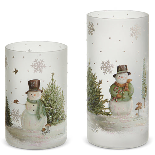A set of two glass woodland snowman candle holder containers with one larger and one smaller, both featuring a snowman design, frosted glass, and decorative snowflakes.