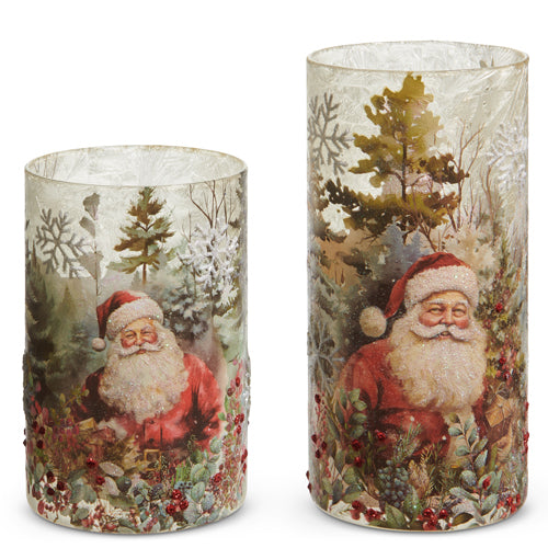 A set of two glass candle holders with a Christmas theme, featuring an illustration of Santa Claus and winter landscape elements.
