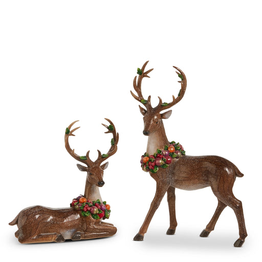 Two deer figurines with floral wreaths on a white background