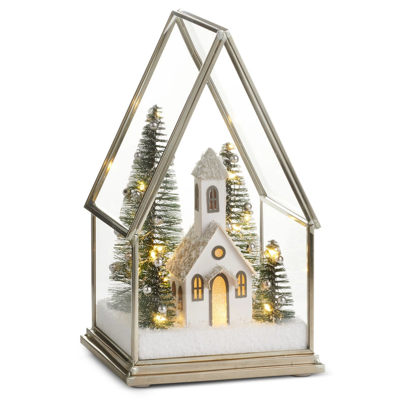 Decorative Christmas scene with a church, trees, and lights inside a glass terrarium on a white background.