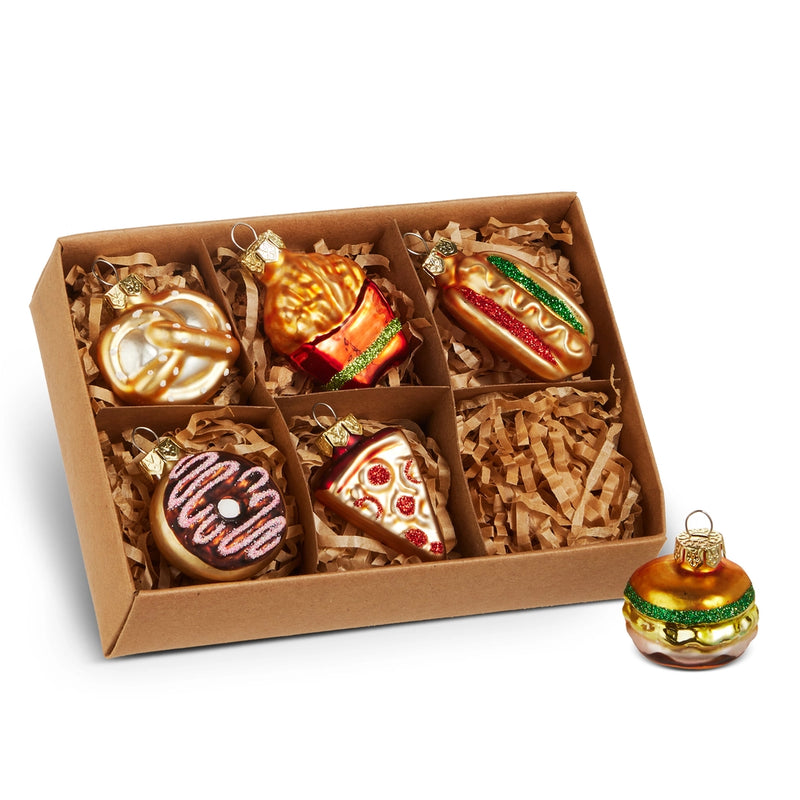 Box of Christmas ornaments shaped like food items on a white background