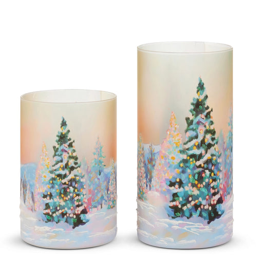 Two cylindrical candles with winter scene design featuring trees and lights on a white background.