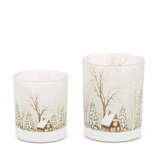 Two decorative candles with winter scene prints on a white background