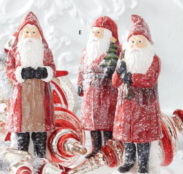 Three Santa Claus figurines with candy canes and a candy sack on a snowy background