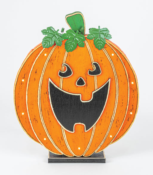 A decorative jack-o'-lantern pumpkin sign with a carved face, green leaves, and a small black base, photographed against a plain light background.