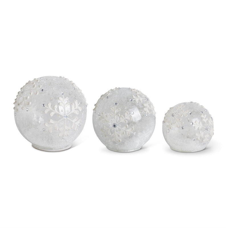 Three clear LED snowflake tabletop glass globes of varying sizes, with a white background.
