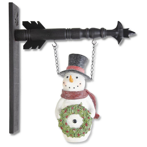 Decorative snowman with a wreath hanging from a black metal bracket on a white background