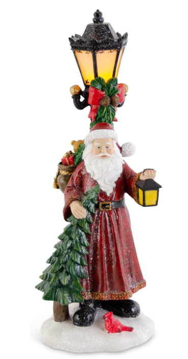 Decorative figurine of Santa Claus with a street lamp and Christmas tree on a white background