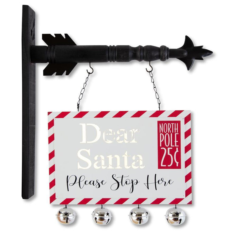 Decorative sign with 'Dear Santa Please Stop Here' text and bell attachments on a white background
