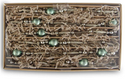 Box of decorative green and silver beads on a white background