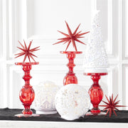 Decorative items including red candle holders, white spherical ornaments, and star-shaped decorations on a black surface.