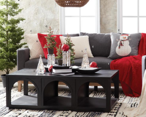 Living room with a gray sofa, black coffee table, and Christmas decorations.