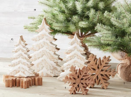 Decorative Christmas trees and snowflakes on a wooden surface with a Christmas tree in the background.