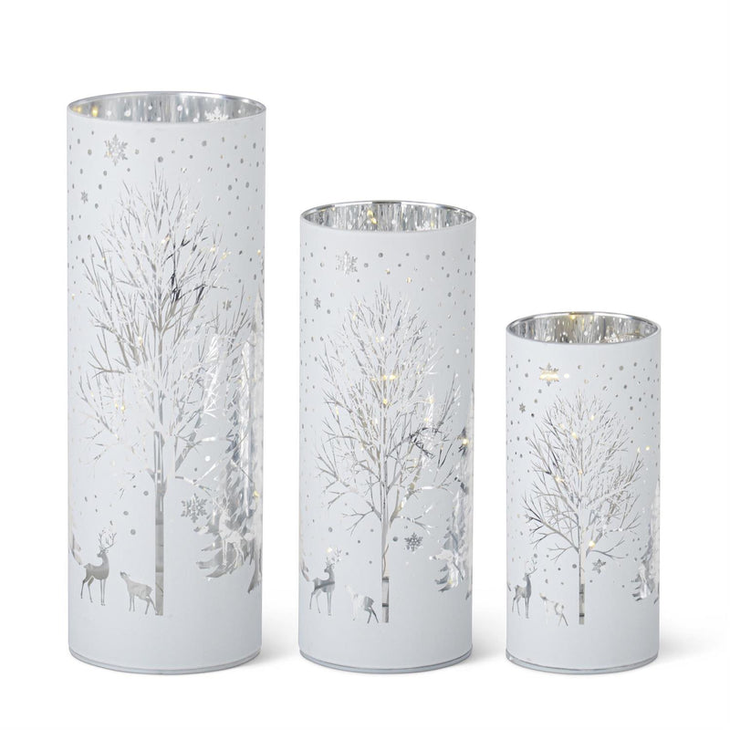 Set of three white LED cylinders with laser engraved winter scenes, including trees and snow.