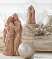 Decorative angel figurines with a glittery sphere and tinsel on a white surface.