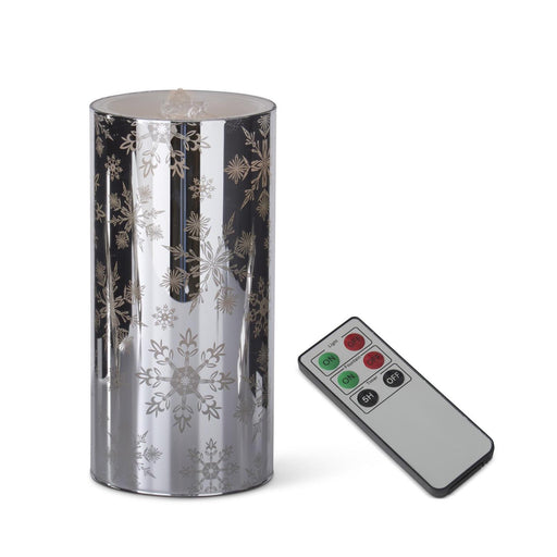 Decorative cylindrical lantern with snowflake patterns and a remote control on a white background